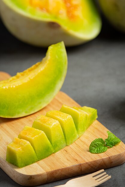 Frische Melone, in Stücke geschnitten, auf Holzschneidebrett legen