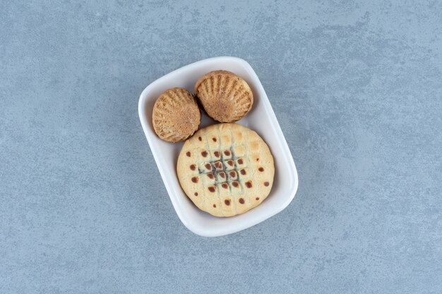 Frische Muffins mit Plätzchen in weißer Schüssel.