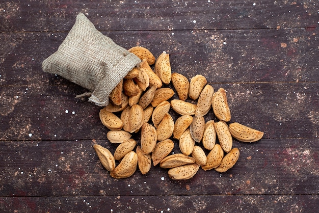 Frische Nüsse von oben, gesalzen und lecker auf der dunklen hölzernen Schreibtischnuss-Snackschale