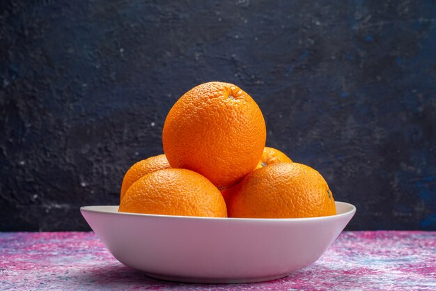 Frische Orangen der Vorderansicht innerhalb der weißen Platte auf Dunkelheit