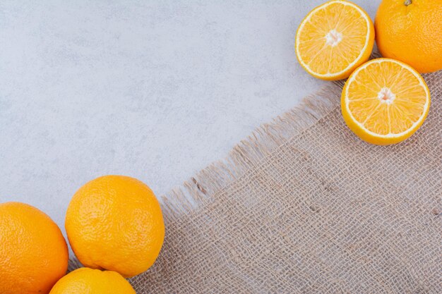 Frische Orangen, die auf Sackleinen auf weißem Hintergrund liegen. Foto in hoher Qualität