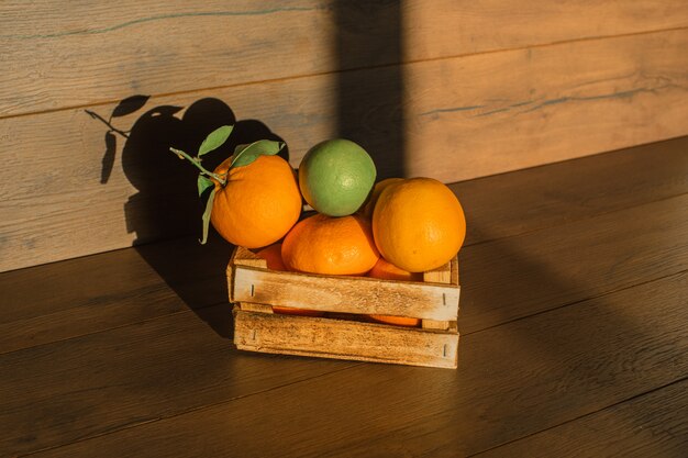 Frische Orangen in der natürlichen Beleuchtung der Holzkiste auf einer Holzoberfläche