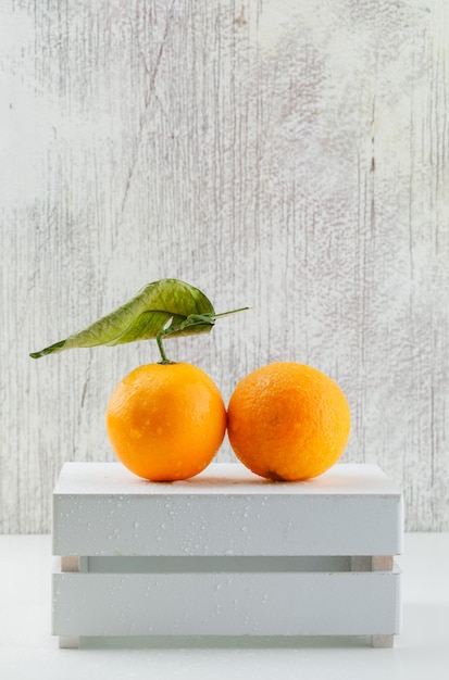 Kostenloses Foto frische orangen mit blatt auf einer holzkiste, seitenansicht.