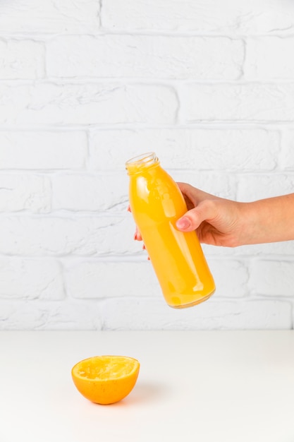 Frische Orangensaftflasche von Person gehalten