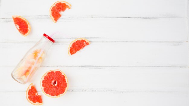 Frische Pampelmusen und Orangen in der Nähe von Flasche