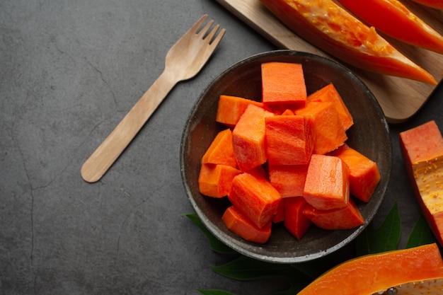 Frische Papaya, in Stücke geschnitten, auf einen schwarzen Teller legen.