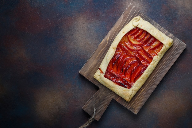 Frische Pflaume Galette Torte mit rohen Pflaumen auf Dunkelheit