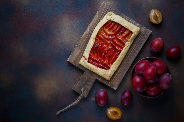 Frische Pflaume Galette Torte mit rohen Pflaumen auf Dunkelheit