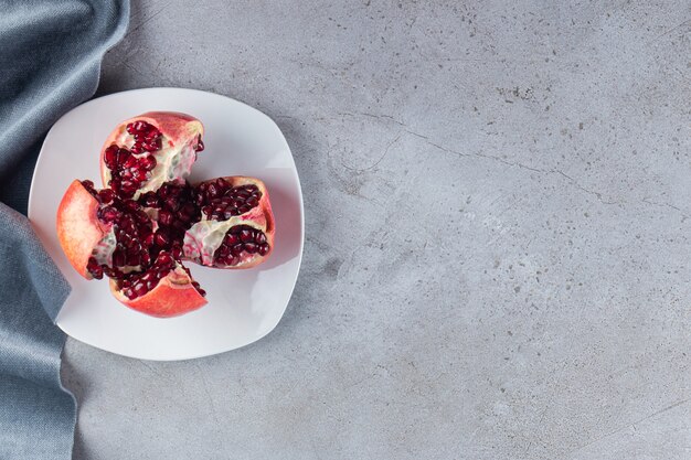 Frische reife Granatäpfel mit Samen auf weißen Teller gelegt.