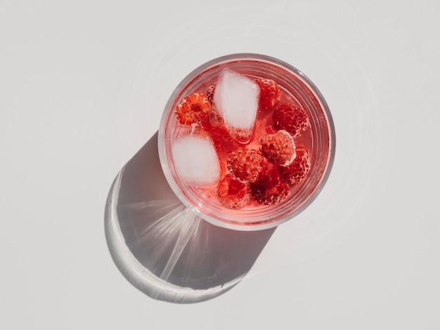 Kostenloses Foto frische reife himbeeren und himbeersaft in einem glas mit eiswürfeln