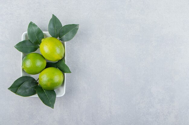 Frische reife Limetten auf weißem Teller.