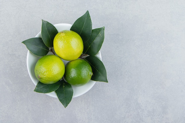 Frische reife Limetten in weißer Schüssel