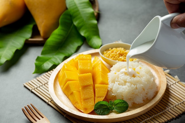 Frische reife Mango und Klebreis mit Kokosmilch auf dunkler Oberfläche