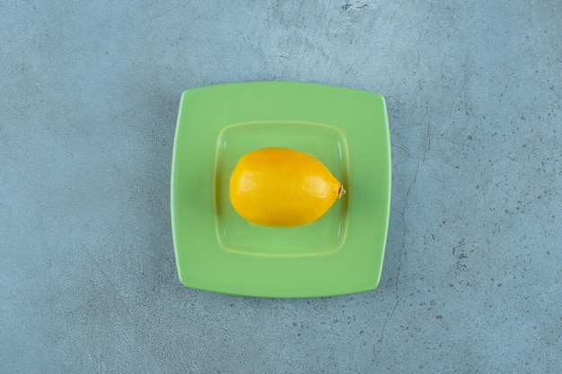 Frische reife Zitrone auf einem Untersetzer, auf dem Marmorhintergrund. Foto in hoher Qualität