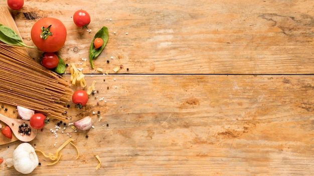 Frische rohe italienische Bestandteile mit Spaghettiteigwaren über strukturierter Tabelle