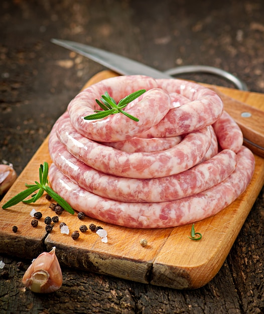 Frische rohe Wurst auf dem alten hölzernen Hintergrund