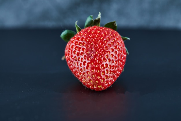 Frische rote Erdbeere auf dunkler Oberfläche. Nahansicht