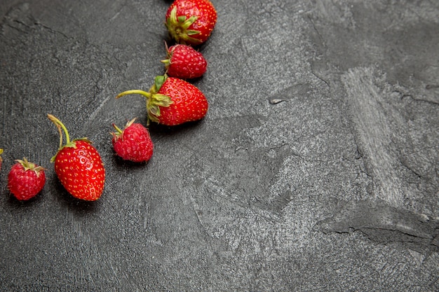 Kostenloses Foto frische rote erdbeeren der vorderansicht gezeichnet auf dunkelgrauem hintergrund