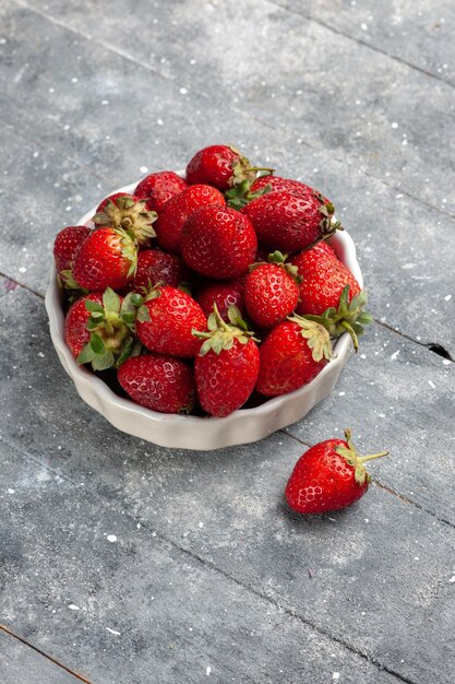 frische rote Erdbeeren milde und reife Früchte innerhalb Platte auf grauem Schreibtisch