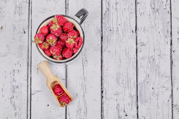 Frische rote Himbeeren auf Becher auf Holztisch.