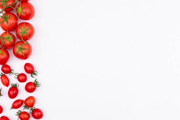 Frische rote Tomaten auf der linken Seite der weißen Oberfläche der Rahmengrenze breiteten tomotoes aus