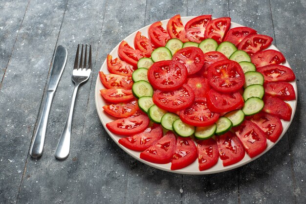 Frische rote Tomaten der Vorderansicht geschnittenen frischen Salat auf rustikalem grauem Schreibtisch