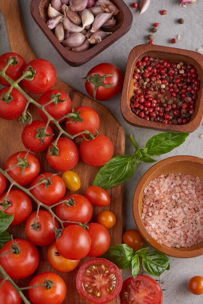 Frische rote Tomatensorte mit Basilikumgewürzen, Pfeffer. Tomatengemüse-Konzept. Vegane Diätnahrung. Tomaten ernten.
