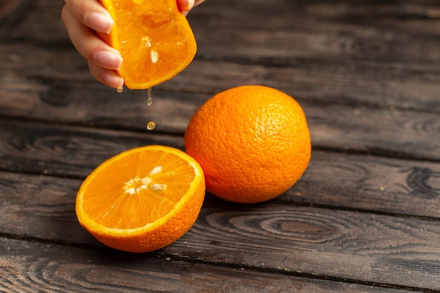 Frische saure Orangen der Vorderansicht saftig und weich isoliert auf dem braunen rustikalen Hintergrundfruchtzitrusfruchttropenfrischsaft