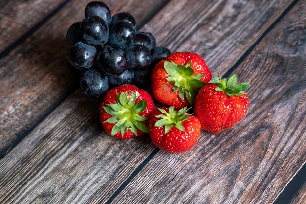 Frische schottische Erdbeeren und schwarze Trauben auf Holztisch