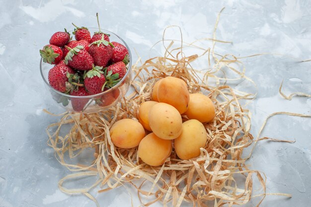 frische süße Aprikosen milde Früchte mit roten Erdbeeren auf Weiß