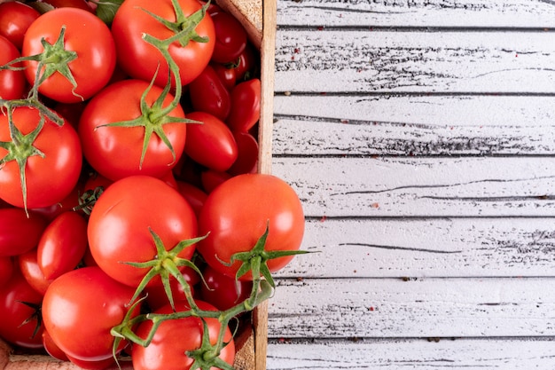 Kostenloses Foto frische tomaten in der holzkiste auf weißer holzoberfläche