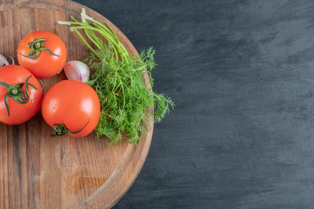 Frische Tomaten mit Knoblauch auf einem Holzbrett.