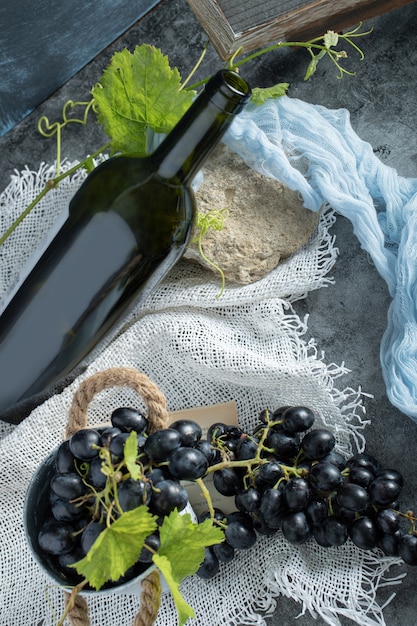 Frische Trauben im Eimer mit Flasche Wein auf Sackleinen