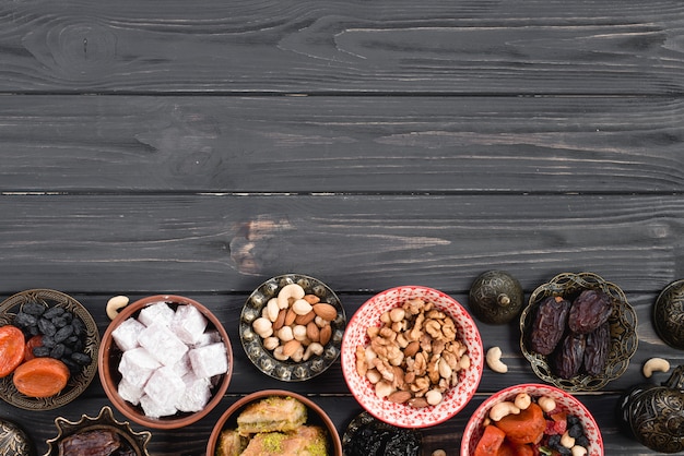 Kostenloses Foto frische türkische trockenfrüchte; nüsse; süßigkeiten für ramadan auf schwarzem holzschreibtisch