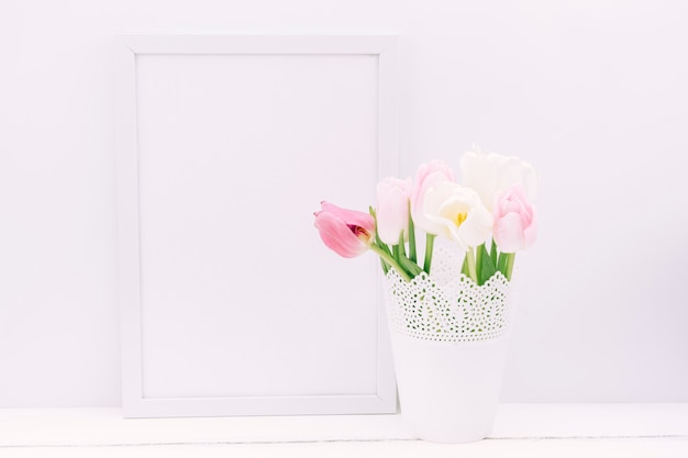 Frische Tulpenblumen im Vase mit leerem Fotorahmen