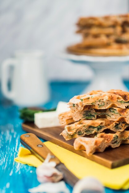 Frische würzige Waffeln auf Schneidebrett mit Messer und Knoblauchzehen