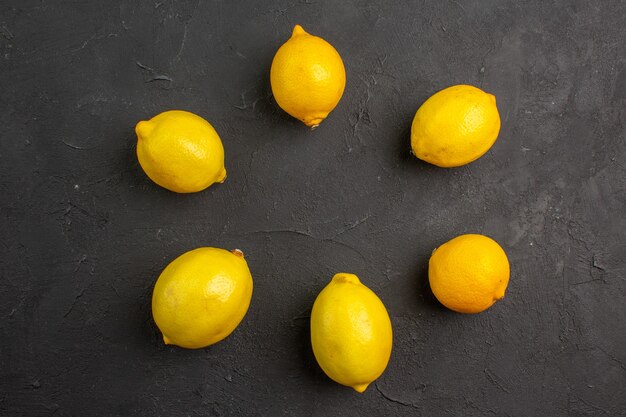 Frische Zitronen der Draufsicht, die auf exotischen Zitrusgelbfrüchten des dunklen Tisches ausgekleidet sind