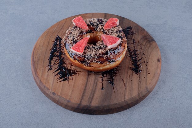 Frischer Donut mit Grapefruitscheiben auf Holzbrett