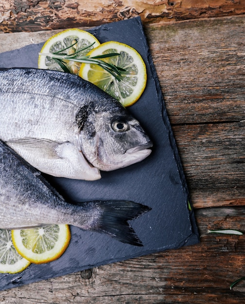 frischer Fisch mit Zitrone auf rustikalem Brett