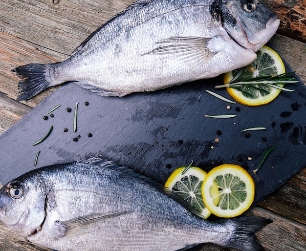 frischer Fisch mit Zitrone auf rustikalem Brett