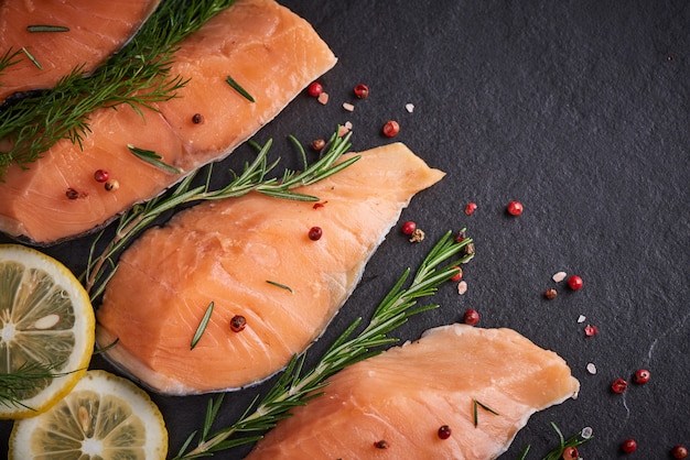 Kostenloses Foto frischer fisch. stück rohes lachsfischfilet, gewürze auf schwarzer steinoberfläche, leckeres fischfleisch. draufsicht. gesundes essen.