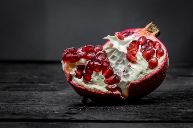 Frischer gebrochener Granatapfel auf Schwarzem, Makro