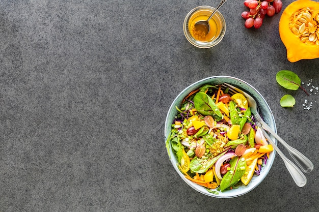 Frischer Gemüse- und Obstsalat in einem Teller auf einem schwarzen Steintisch. Draufsicht