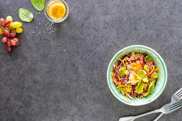 Frischer Gemüse- und Obstsalat in einer Platte auf schwarzem Steinhintergrund Draufsicht