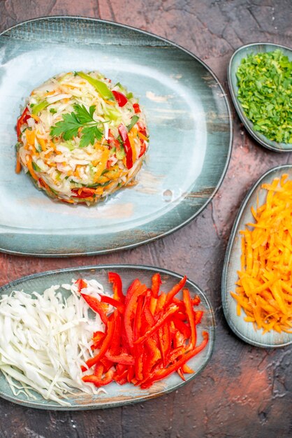 Frischer Gemüsesalat der Draufsicht mit geschnittenem Karottenkohl und Paprika auf dem dunklen Tisch