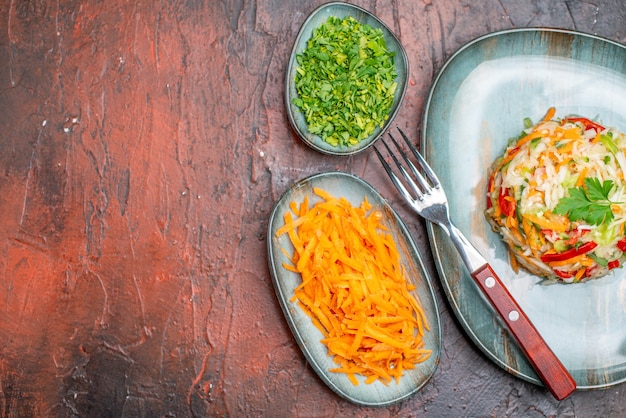 Kostenloses Foto frischer gemüsesalat der draufsicht mit grüns auf dunklem tisch