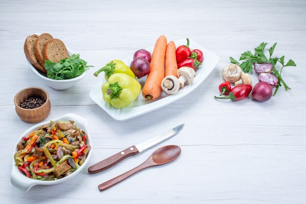 Frischer gemüsesalat in scheiben geschnitten mit fleisch zusammen mit brotlaib und ganzem gemüse und gemüse auf leichtem schreibtisch, essen mahlzeit salat vitamin