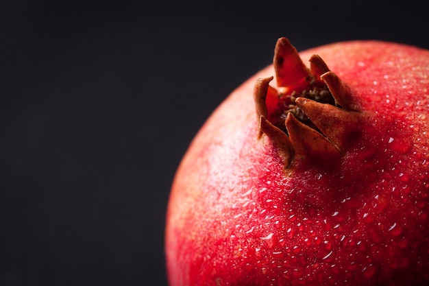 Kostenloses Foto frischer granatapfel mit wassertropfen auf einem dunklen hintergrund