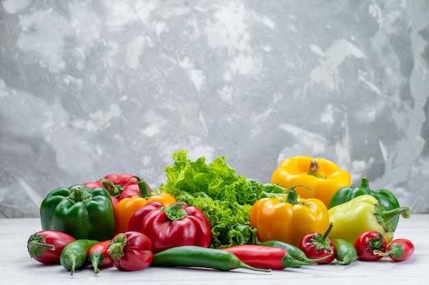 Kostenloses Foto frischer grüner salat zusammen mit farbigen paprika und würzigen paprika zusammensetzung auf hellem schreibtisch
