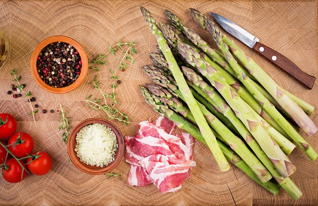 Frischer grüner Spargel und Speck auf einem rustikalen Holztisch mit Kopienraum. Draufsicht